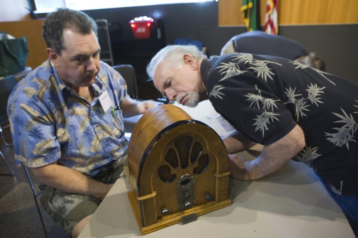 Volunteers Neil Sedell and Dave Meigs look at an old radio as they attempt to repair it during a 2017 event at the Vancouver Community Library.