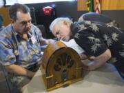 Volunteers Neil Sedell and Dave Meigs look at an old radio as they attempt to repair it during a 2017 event at the Vancouver Community Library.