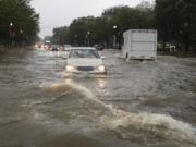 Heavy rainfall flooded the intersection of 15th Street and Constitution Ave., NW, stalling cars in the street, Monday, July 8, 2019, in Washington.