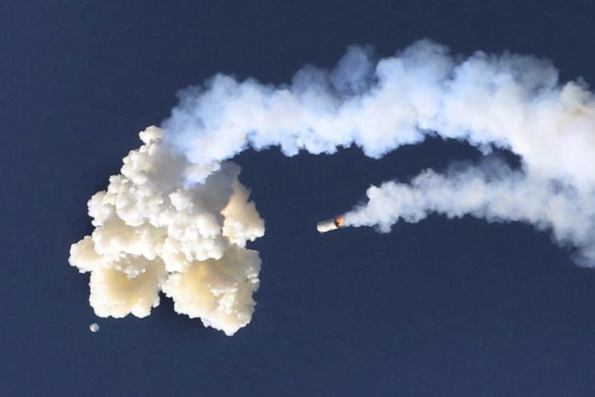 The Orion test capsule, bottom left, and a Minotaur 4 booster rocket, center, fall to the Earth, Tuesday, July 2, 2019, as NASA conducted a full-stress launch abort test in Cape Canaveral, Fla., for the capsule designed to carry astronauts to the moon The capsule was empty for the morning demo, which officials said appeared to be successful.