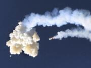 The Orion test capsule, bottom left, and a Minotaur 4 booster rocket, center, fall to the Earth, Tuesday, July 2, 2019, as NASA conducted a full-stress launch abort test in Cape Canaveral, Fla., for the capsule designed to carry astronauts to the moon The capsule was empty for the morning demo, which officials said appeared to be successful.