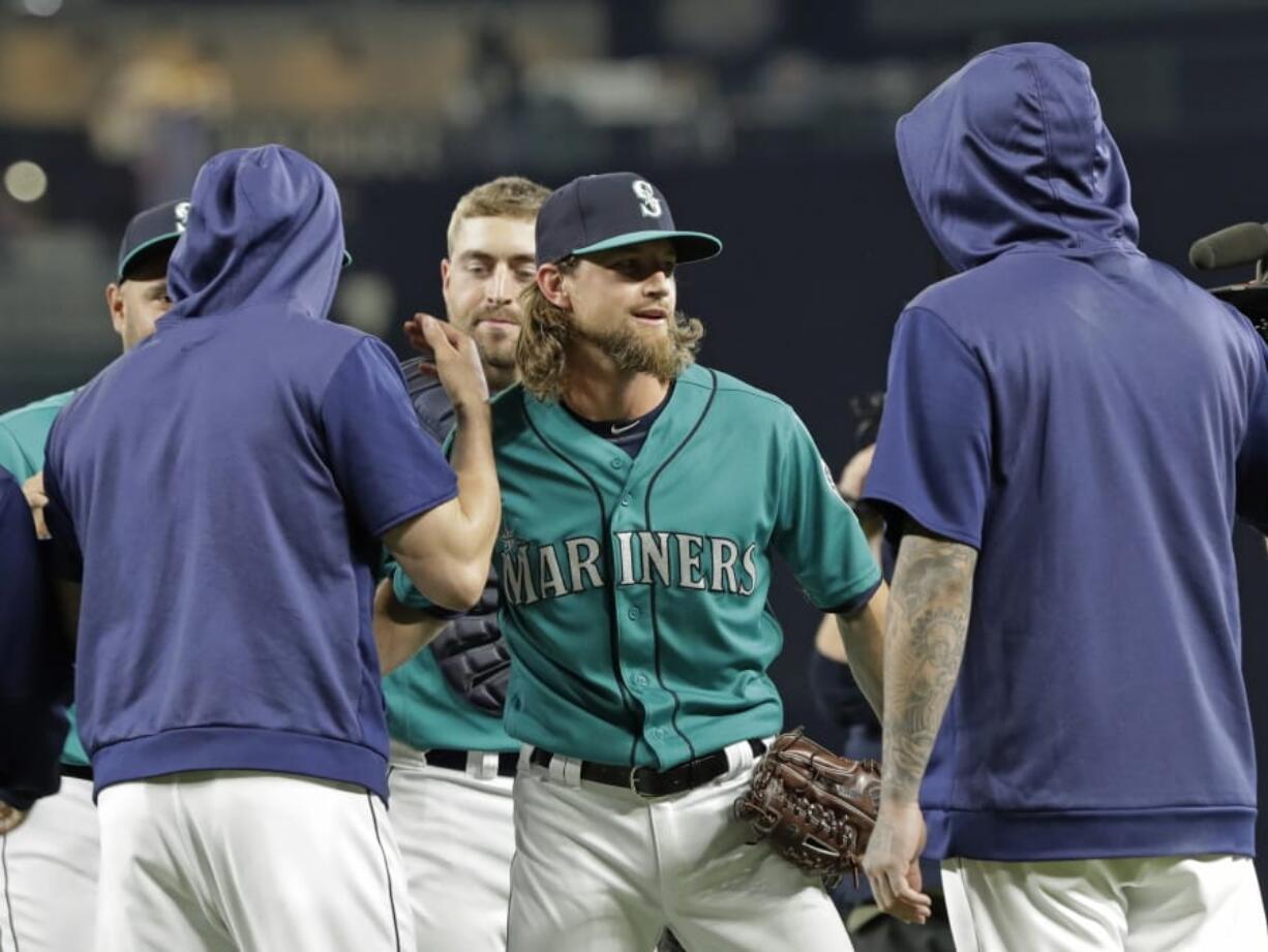 Seattle Mariners starting pitcher Mike Leake, center, is greeted by teammates after he threw a one-hitter against the Los Angeles Angels in a baseball game Friday, July 19, 2019, in Seattle. The Mariners won 10-0. (AP Photo/Ted S.