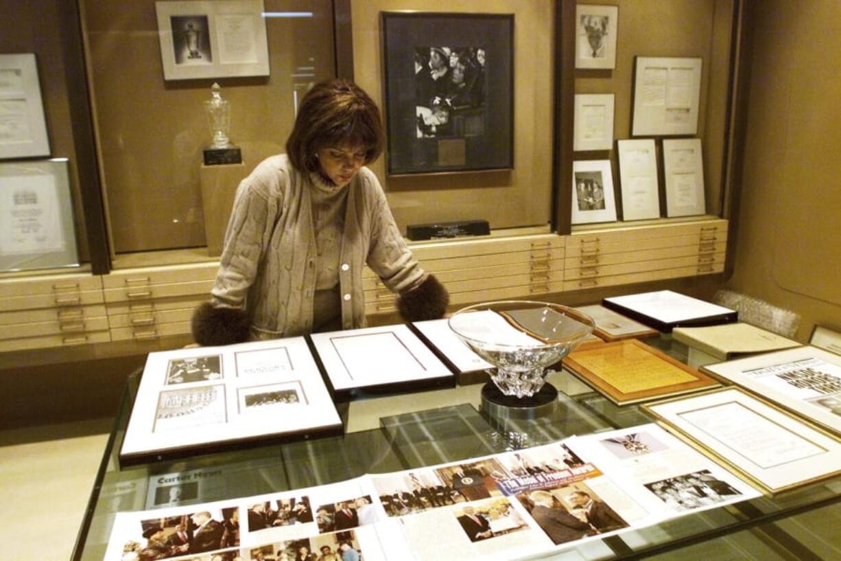 FILE - In this Dec. 10, 2001 file photo Linda Johnson Rice, president and chief operating officer of Jet magazine, looks over awards and recognitions won by the magazine in its 50-year lifetime at Jet’s Chicago headquarters. The sale of the photo archive of Ebony and Jet magazines chronicling African American history is generating relief among some who worried the historic images may be lost. But it’s also causing some to mourn the fact that the prints won’t fully be in the hands of an African American-owned entity. (AP Photo/Ted S.