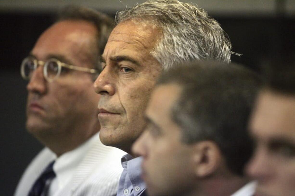 FILE - In this July 30, 2008 file photo, Jeffrey Epstein, center, is shown in custody in West Palm Beach, Fla. The wealthy financier and convicted sex offender has been arrested in New York on sex trafficking charges. Two law enforcement officials said Epstein was taken into federal custody Saturday, July 6, 2019, on charges involving sex-trafficking allegations that date to the 2000s.