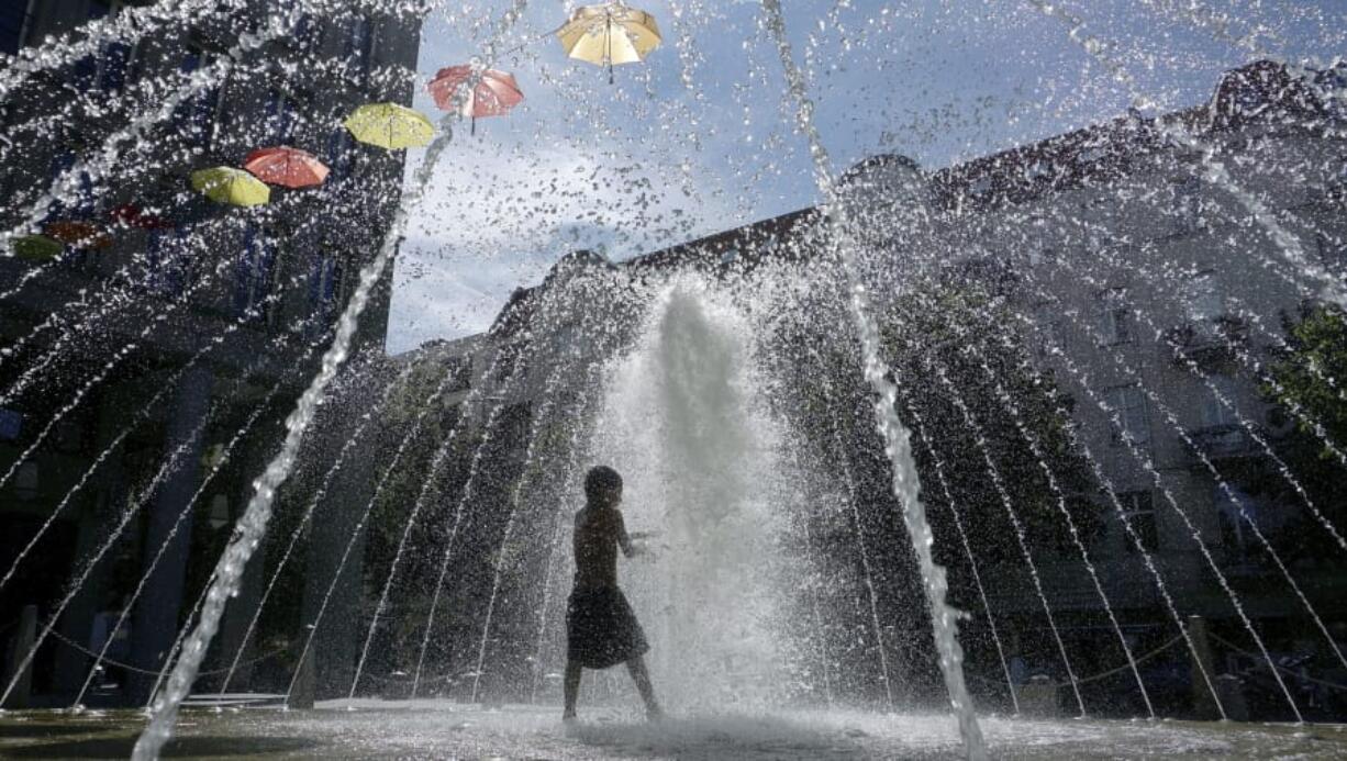 A boy plays in a fontaine in Berlin, Germany, Wednesday, July 24, 2019.