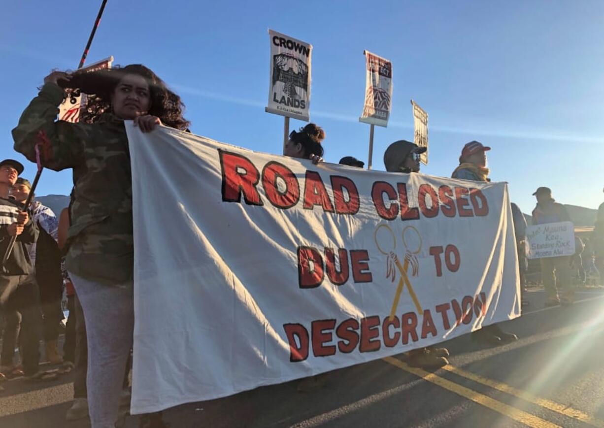 Demonstrators gather to block a road at the base of Hawaii's tallest mountain, Monday, July 15, 2019, in Mauna Kea, Hawaii, to protest the construction of a giant telescope on land that some Native Hawaiians consider sacred.