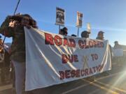 Demonstrators gather to block a road at the base of Hawaii's tallest mountain, Monday, July 15, 2019, in Mauna Kea, Hawaii, to protest the construction of a giant telescope on land that some Native Hawaiians consider sacred.