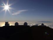 FILE - In this Sunday, July 14, 2019, file photo, the sun sets behind telescopes at the summit of Mauna Kea. Scientists are expected to explore fundamental questions about our universe when they use a giant new telescope planned for the summit of Hawaii’s tallest mountain. That includes whether there’s life outside our solar system and how stars and galaxies formed in the earliest years of the universe. But some Native Hawaiians don’t want the Thirty Meter Telescope to be built at Mauna Kea’s summit, saying it will further harm a place they consider sacred.