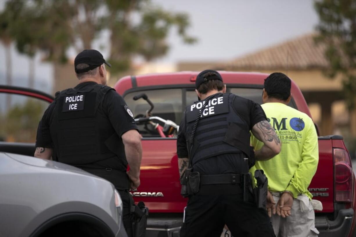 U.S. Immigration and Customs Enforcement officers detain a man during an operation July 8 in Escondido, Calif.