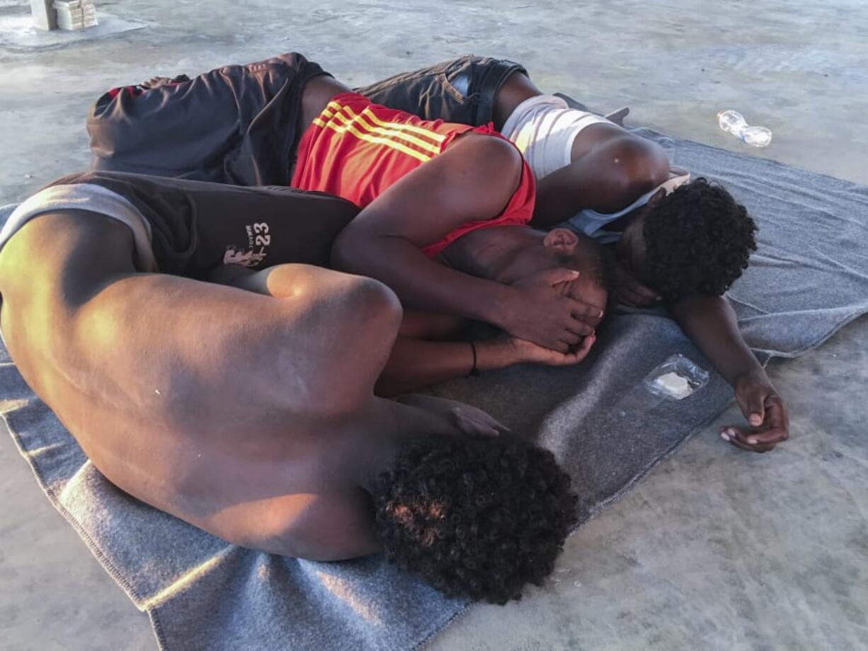 Rescued migrants rest on a coast some 100 kilometers (60 miles) east of Tripoli, Libya, Thursday, July 25, 2019. The U.N. refugee agency and the International Rescue Committee say up to 150 may have perished at sea off the coast of Libya. The country’s coast guard says the Europe-bound migrants are missing and feared drowned after the boats they were traveling on capsized in the Mediterranean Sea. A spokesman says they rescued around 137 migrants on Thursday.