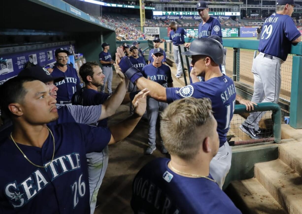 Seattle Mariners’ Kyle Seager, right, is congratulated in the dugout after scoring on a Tom Murphy single during the seventh inning of the team’s baseball game against the Texas Rangers in Arlington, Texas, Tuesday, July 30, 2019.