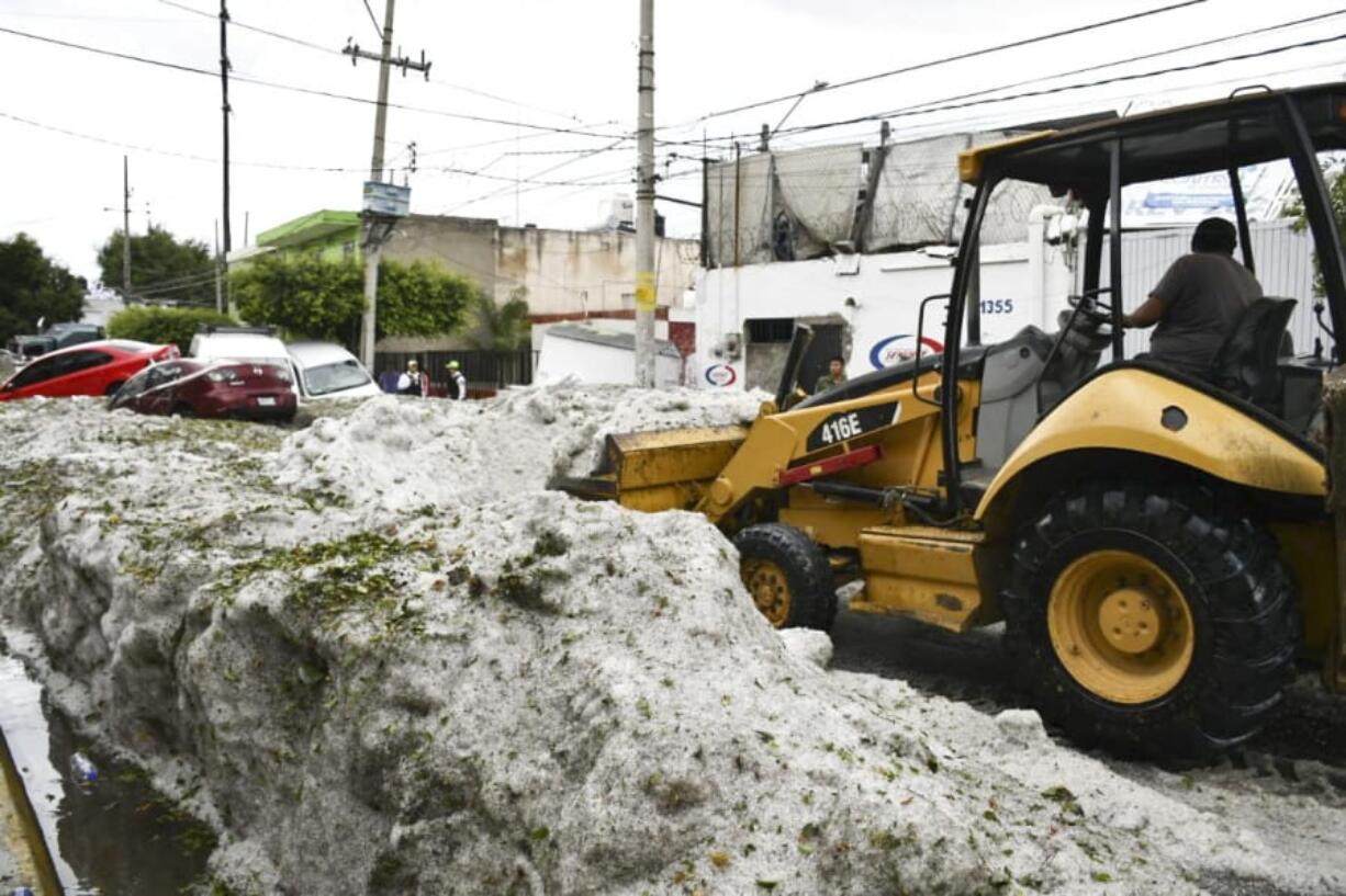 In this photo released by Jalisco State Civil Defense Agency, a bulldozer removes hail filling the streets of Guadalajara, Mexico, Sunday, June 30, 2019. Officials in Mexico’s second largest city say a storm that dumped more than a meter of hail on parts of the metropolitan area damaged hundreds of homes.