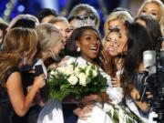 FILE - This Sept. 9, 2018 file photo shows Miss New York Nia Franklin, center, reacting after being named Miss America 2019 in Atlantic City, N.J. The Miss America Organization says this year’s pageant will be held at the Mohegan Sun Connecticut in Uncasville, Connecticut. It will be broadcast on NBC Dec. 19, in a switch from recent broadcaster ABC. (AP Photo/Noah K.