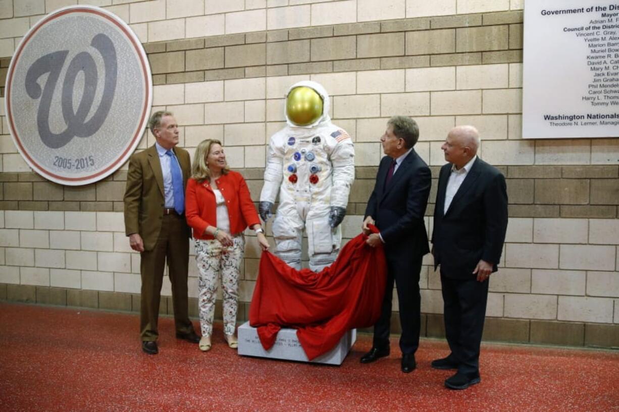 FILE - In this June 4, 2019 file photo, Washington Nationals senior vice president Gregory McCarthy, from left, Ellen Stofan of the National Air and Space Museum, statue donor Allan Holt and Nationals owner Mark Lerner unveil a statue of Neil Armstrong’s Apollo 11 spacesuit before an interleague baseball game between the Chicago White Sox and the Nationals in Washington. It was unveiled as part of the “Apollo at the Park” program, which will place statues of Armstrong’s spacesuit at ballparks across the country to commemorate the moon landing’s 50th anniversary.