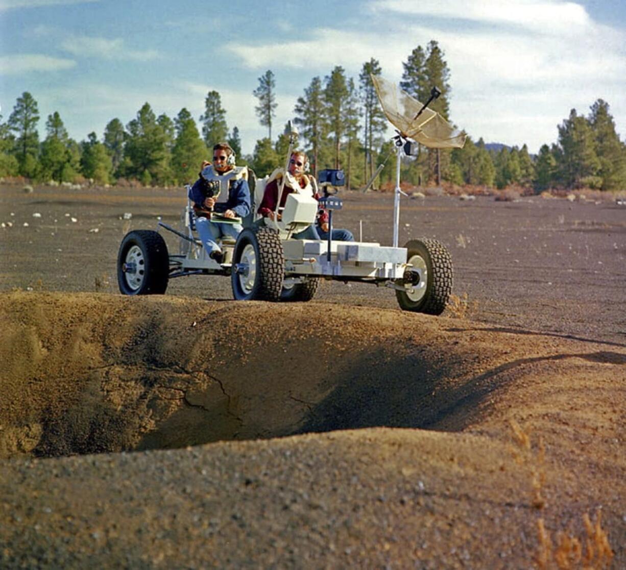 This undated photo provided by the U.S. Geological Survey Astrogeology Science Center shows Apollo 15 astronauts Jim Irwin, left, and Dave Scott driving a prototype of a lunar rover in a volcanic cinder field east of Flagstaff, Ariz. The rover, named Grover, now is on display at the science center. (U.S.