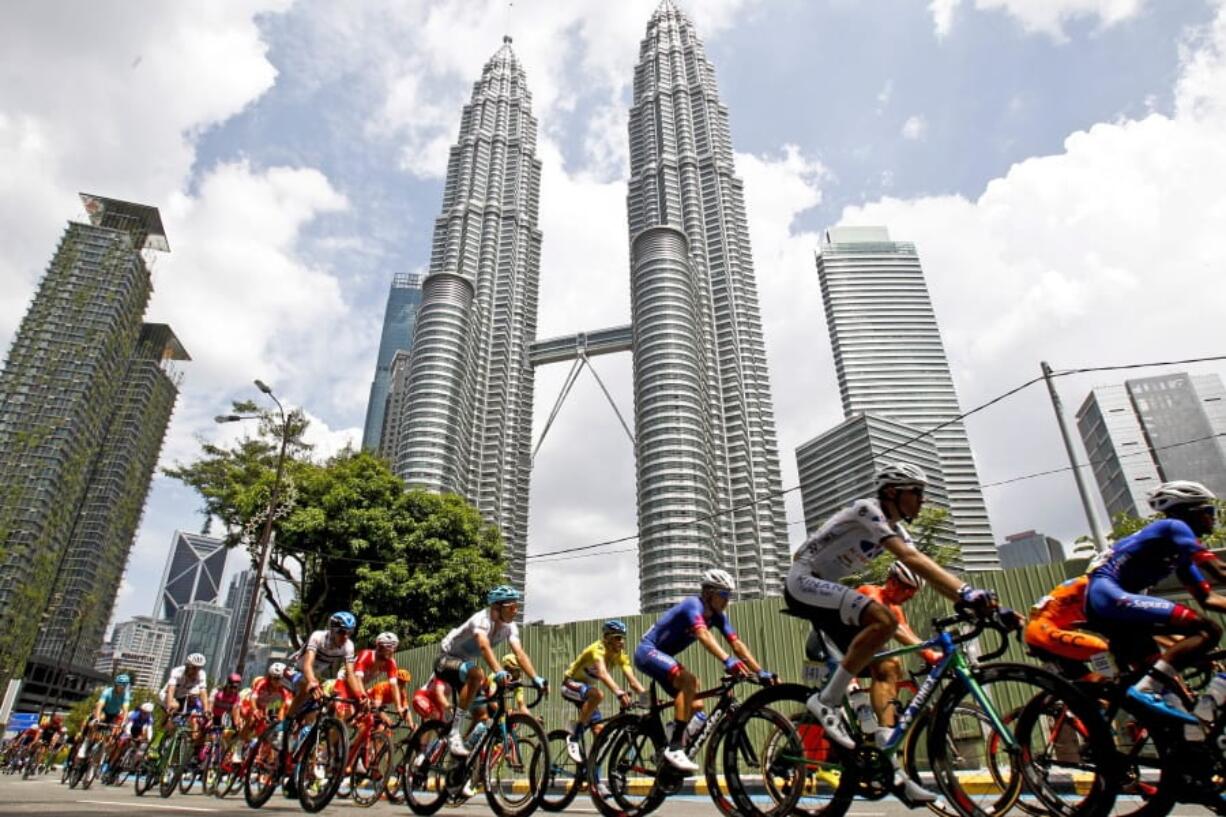 FILE - In this March 25, 2018 file photo, cyclists move past Malaysia’s landmark Petronas Twin Towers during the last stage of Le Tour de Langkawi cycling race in Kuala Lumpur, Malaysia. Architect César Pelli, renowned for designing some of the world’s tallest buildings, including the Petronas Twin Towers, has died, Friday, July 19, 2019, his firm said.