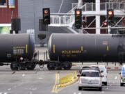 FILE - In this Feb. 13, 2018, file photo, automobile traffic waits at a train crossing as train cars that carry oil are pulled through downtown Seattle. Attorneys general for North Dakota and Montana have petitioned the Trump administration Wednesday, July 17, 2019, to overrule a Washington state law that imposes safety restrictions on oil shipped by rail from the Northern Plains.