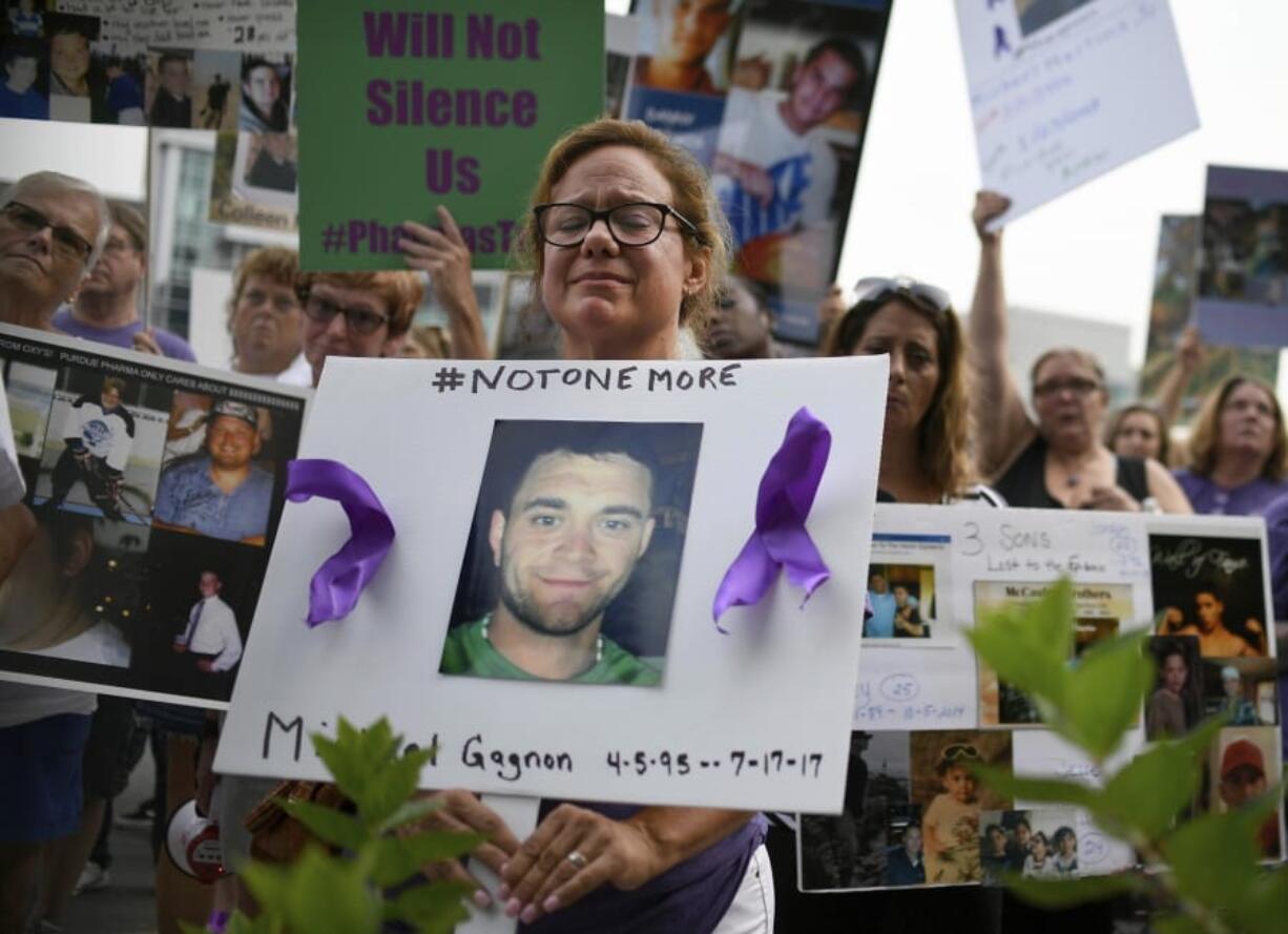 FILE - In this Aug. 17, 2018 file photo, Christine Gagnon, of Southington, Conn., holds a sign during a protest with others who have lost loved ones to OxyContin and opioid overdoses, outside the Purdue Pharma headquarters in Stamford, Conn. Gagnon lost her son Michael 13 months earlier. Nearly ten years ago, the blockbuster painkiller OxyContin was reformulated to discourage abuse by snorting and injecting, but it’s unclear whether the harder-to-abuse format has decreased cases of addiction, overdose and death.