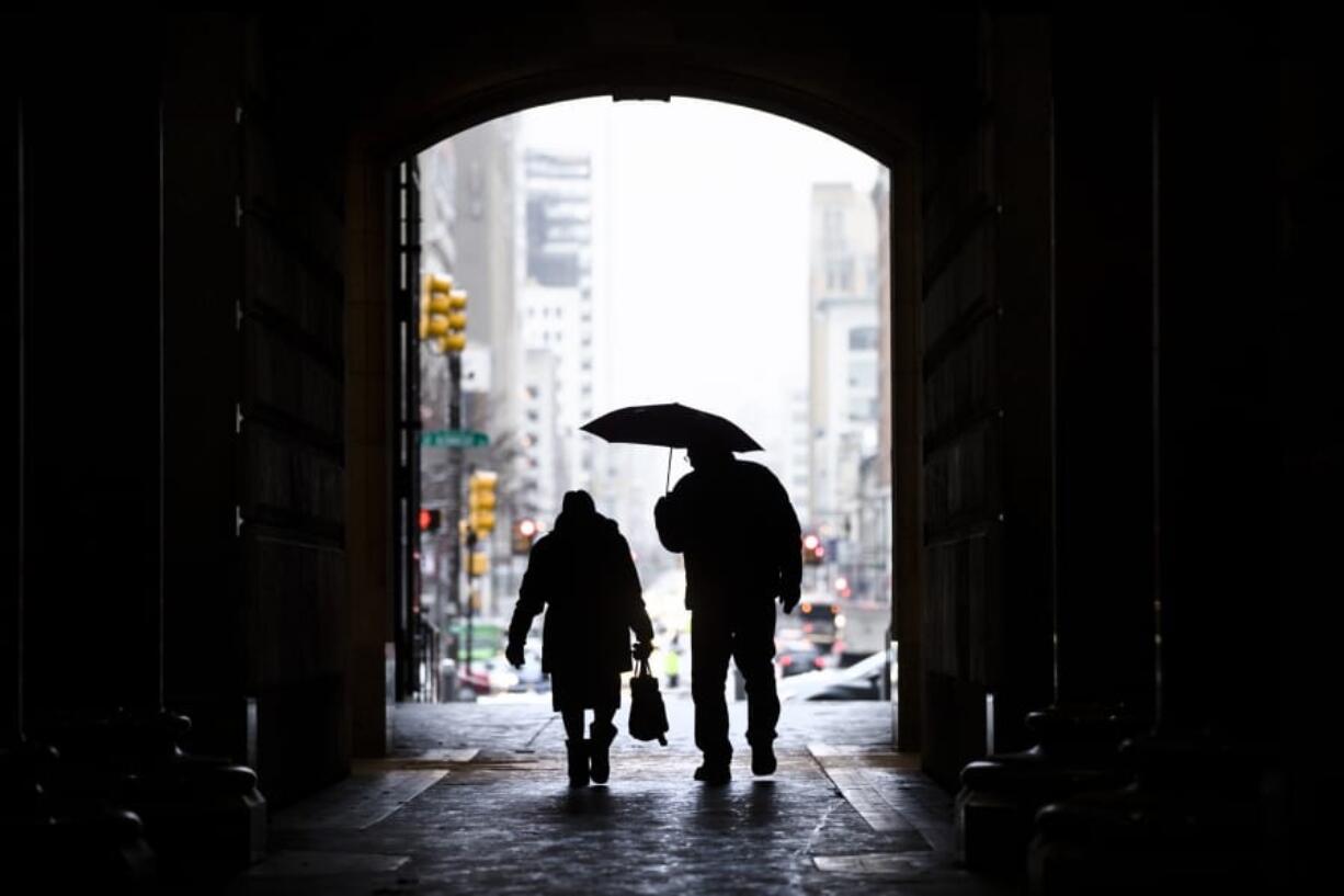 FILE- In this Feb. 12, 2019, file photo pedestrians pass beneath City Hall in Philadelphia. Nearly one-quarter of Americans say they never plan to retire, according to a poll that suggests a disconnect between individuals’ retirement plans and the realities of aging in the workforce.