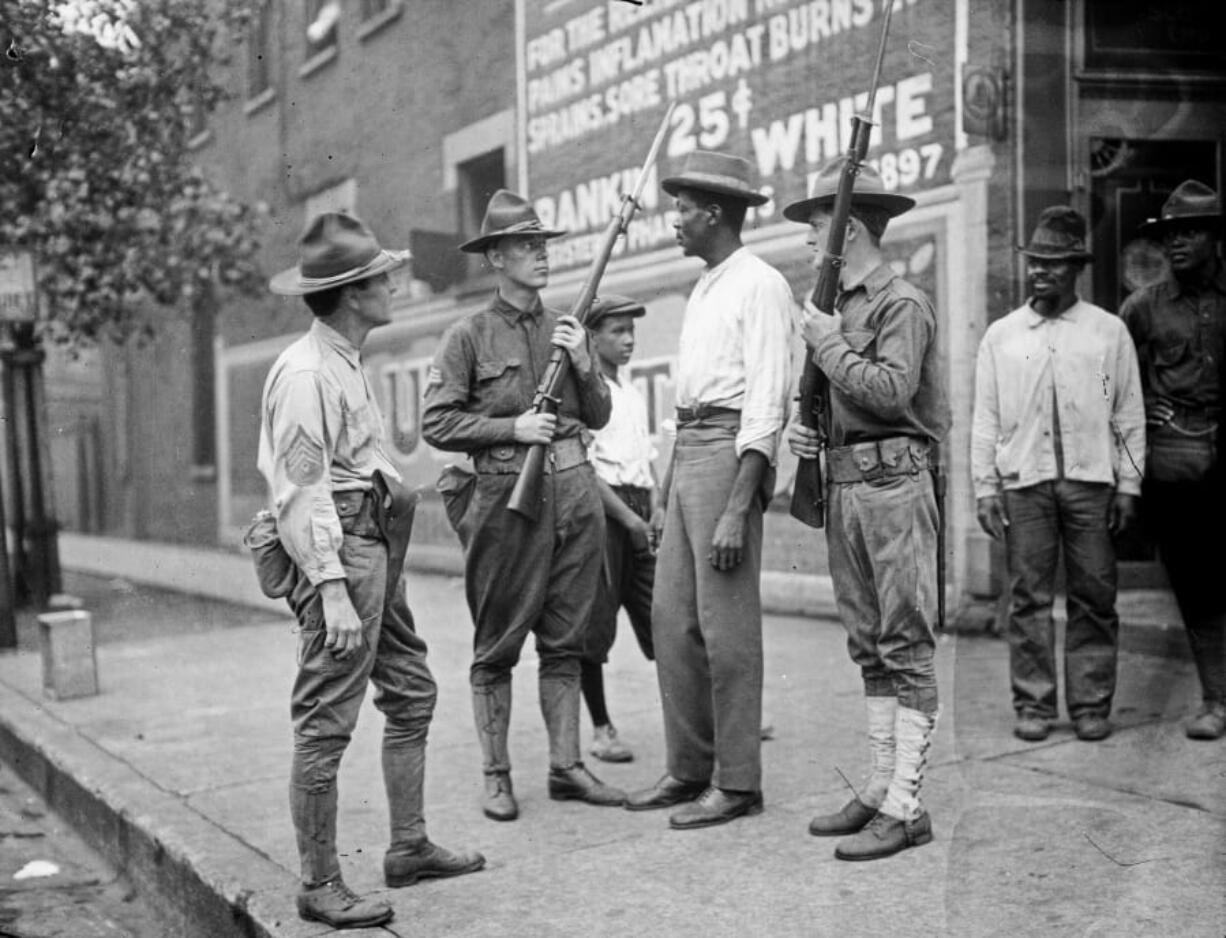 In this 1919 photo provided by the Chicago History Museum, armed National Guard and African American men stand on a sidewalk during race riots in Chicago. It was 100 years ago, in the “Red Summer” of race riots that spread across the United States, but the terror of those days still reverberates in a city that continues to grapple with segregation, housing discrimination, and deep tension between residents and police.