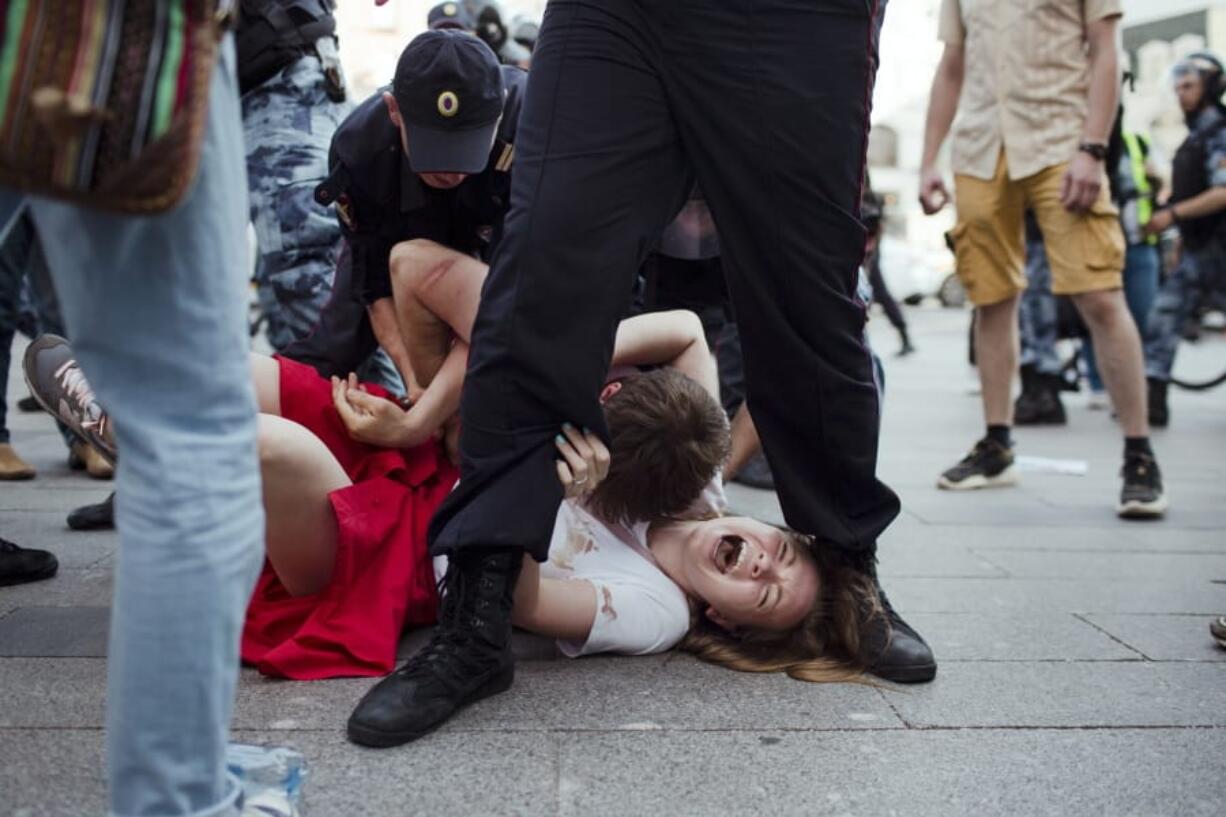 In this photo taken on Saturday, July 27, 2019, Inga Kudracheva screams as her boyfriend Boris Kantorovich lies atop her while police try to detain him during an unsanctioned protest in Moscow. Images of the young couple have been spread on social media. They say the crackdown by police has left them shaken but with their resolve strengthened.