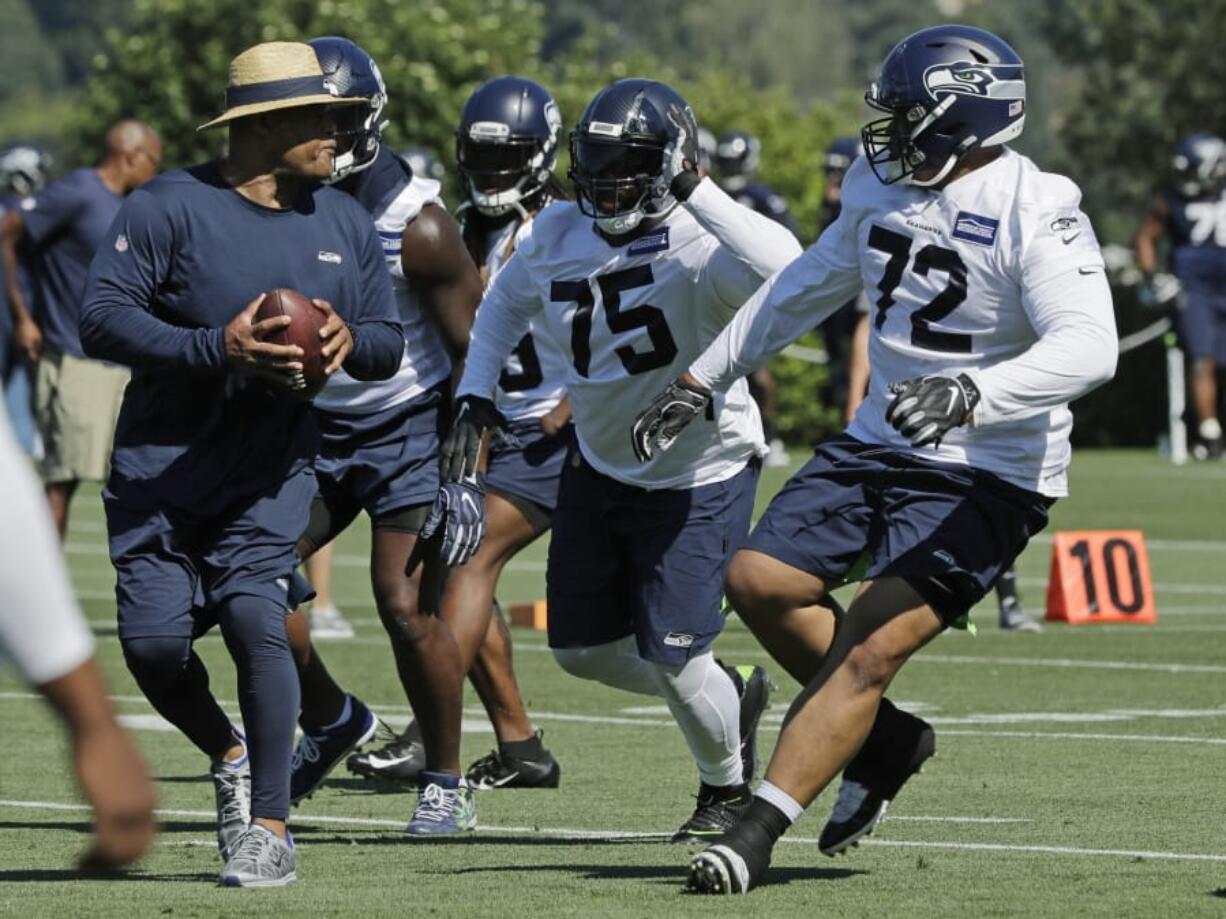 Seattle Seahawks defensive tackles Earl Mitchell (75) and Al Woods (72) work with defensive coordinator Ken Norton Jr., left, during NFL football training camp, Thursday, July 25, 2019, in Renton, Wash. (AP Photo/Ted S.