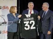 Ron Francis, center, is presented with a hockey jersey by Seattle Mayor Jenny Durkan, left, as Seattle Hockey Partners CEO Tod Leiweke looks on Thursday, July 18, 2019, in Seattle, as Francis is introduced as the first general manager for Seattle’s yet-to-be-named NHL expansion team. Francis, a Hall of Famer and a two-time Stanley Cup winner, will have complete control of operations under Leiweke when the team debuts in 2021. (AP Photo/Ted S.