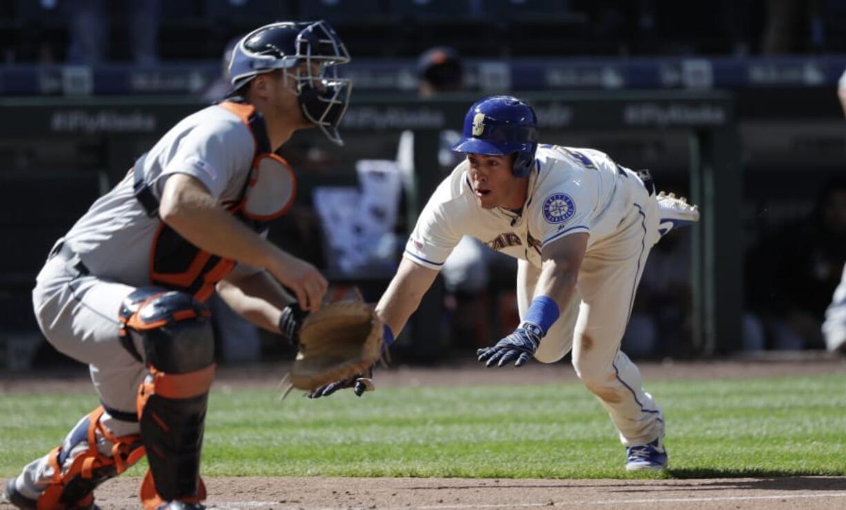 Seattle Mariners’ Dylan Moore, right, dives safely for home to score the winning run as Detroit Tigers catcher John Hicks waits for the ball in the 10th inning of a baseball game Sunday, July 28, 2019, in Seattle.