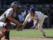 Seattle Mariners’ Dylan Moore, right, dives safely for home to score the winning run as Detroit Tigers catcher John Hicks waits for the ball in the 10th inning of a baseball game Sunday, July 28, 2019, in Seattle.