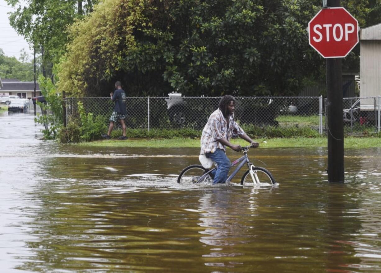 A man tries to bike through the flooding from the rains of storm Barry on LA Hwy 675 in New Iberia, La., Sunday, July 14, 2019. Tropical Depression Barry dumped rain as it slowly swept inland through Gulf Coast states Sunday.