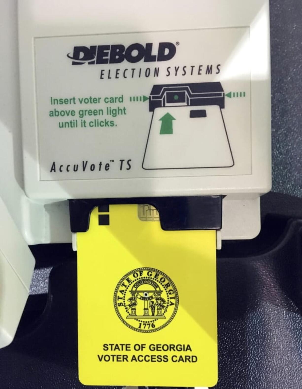 FILE - This May 22, 2018, file photo, shows a voter access card inserted in a reader during voting in the Georgia primary in Kennesaw, Ga. A federal judge is set to hear arguments, Thursday, July 25, 2019, in a lawsuit challenging Georgia’s outdated voting machines and seeking statewide use of hand-marked paper ballots. The hearing will focus on requests for the judge to order the state to immediately stop using the current voting machines.