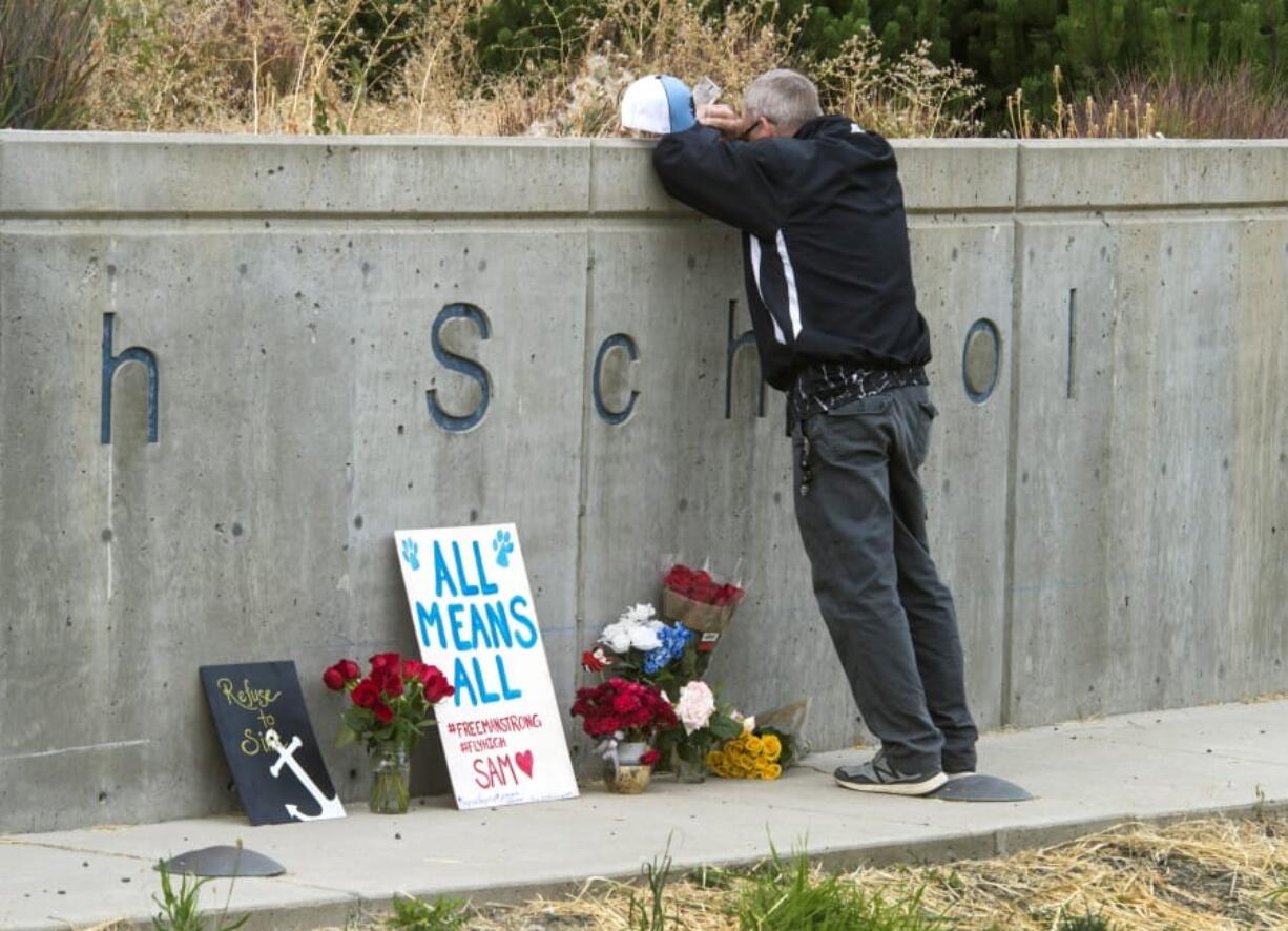 Freeman High School assistant football coach Tim Smetana grieves Sept. 14, 2017, after he placed roses at a memorial following a shooting at the school in Rockford, south of Spokane.