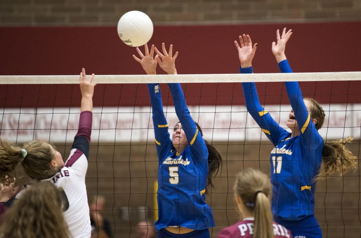 Prairie’s Maddi Cederholm (9) spikes the ball as Kelso’s Sydney Hall (5) and Isabella Hadaller (11) jump to block during Tuesday night’s game at Prairie High School in Camas on Sept. 25, 2018. Prairie won in three sets, 25-10, 25-13, 25-13.