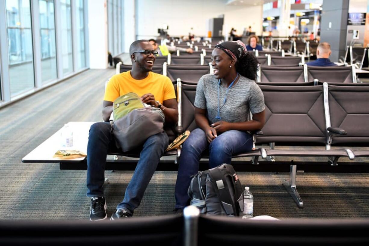 Siblings Malcol and Serene Boachie wait for their flight at Dulles International Airport on Aug. 7. Credit card companies offer enticements to pay for travel and vacations with new cards, but not all deals are really a deal.