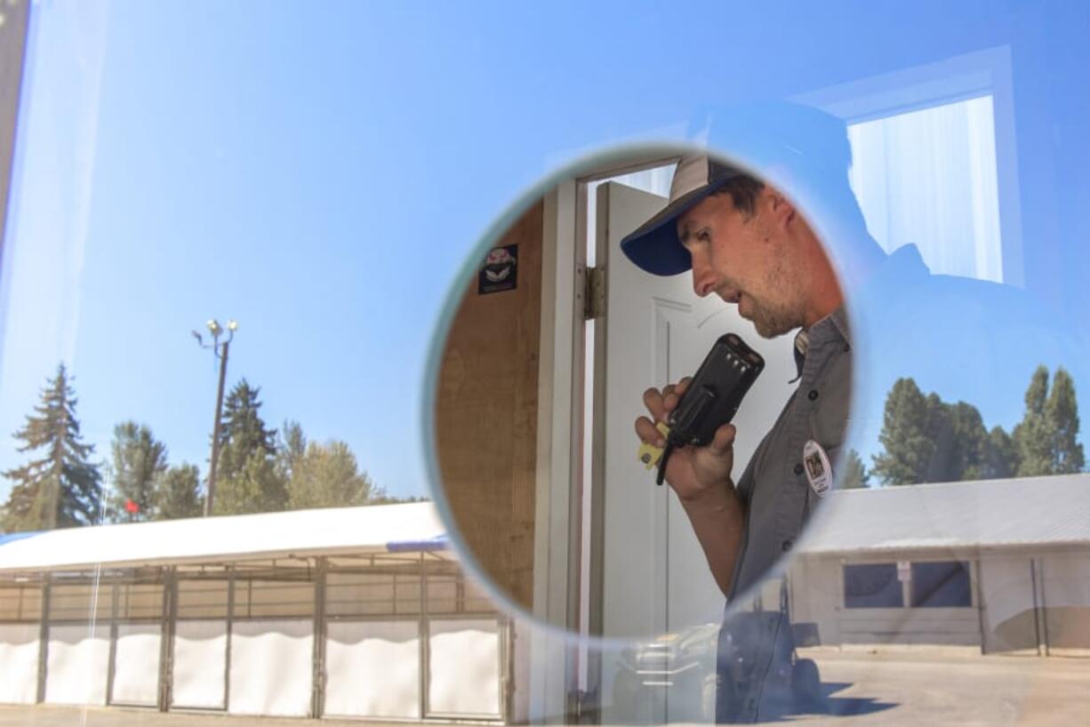 Jason Young, operations superintendent at the Clark County Fair, coordinates setup from his radio while simultaneously helping to set up a ticket booth Thursday, the day before the fair opened. Young’s first job in the event planning world was helping venues in Portland with booking and promotion.