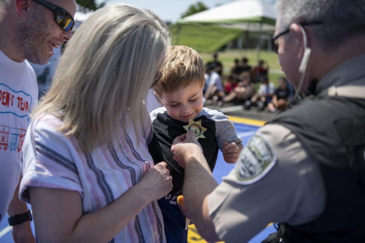 Jeff Linton, from left, and his wife, Erin, watch as their 4-year-old son Camden is named an honorary deputy by Deputy Darrell Benton of the Clark County Sheriff’s Office as part of a Kindness 911 “sting” operation at Skyview High School on Saturday.