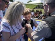 Jeff Linton, from left, and his wife, Erin, watch as their 4-year-old son Camden is named an honorary deputy by Deputy Darrell Benton of the Clark County Sheriff’s Office as part of a Kindness 911 “sting” operation at Skyview High School on Saturday.