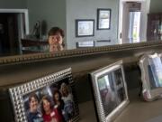 Maria Heckinger looks over important photos while talking about her new memoir. The group photo under the mirror is Heckinger, left, with other Greek adoptees who went searching for their birth parents. They might have been her orphanage playmates in childhood, she said. Now they are close friends.