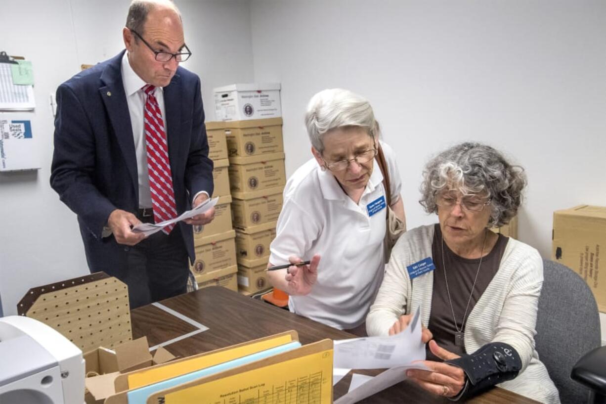 Clark County Auditor Greg Kimsey and observers Karen Hengerer and Edri Geiger, with the League of Women Voters, view the first primary election result printouts in the Clark County Elections office on Tuesday night.