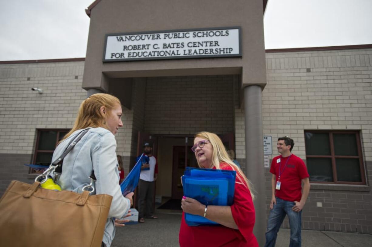 Katie North, a learning support educator at Skyview High School, left, chats with Mona Rominger of the Vancouver Education Association executive board as she attends an educational union meeting at the Bates Center for Educational Leadership on Aug. 9. At top, a colorful button is seen on the T-shirt of Vancouver Education Association executive board member Mona Rominger.