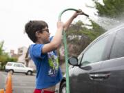 Eight-year-old Eli Bernardi of Ridgefield rinses off his dad's car during the Bottom Half Car Wash at Clark College's Child and Family Studies building on Thursday morning.