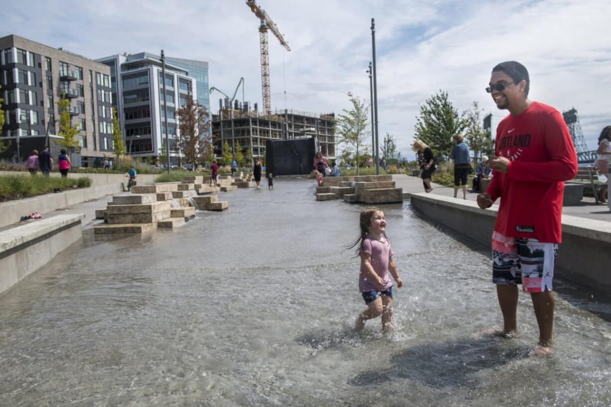 Adaline Sokol, 2, left, and Gage Marshall splash in the new Columbia River water feature Friday afternoon at the Waterfront Vancouver development. The piece opened to the public Friday morning, just in time for passersby to cool their feet in the late-summer heat.