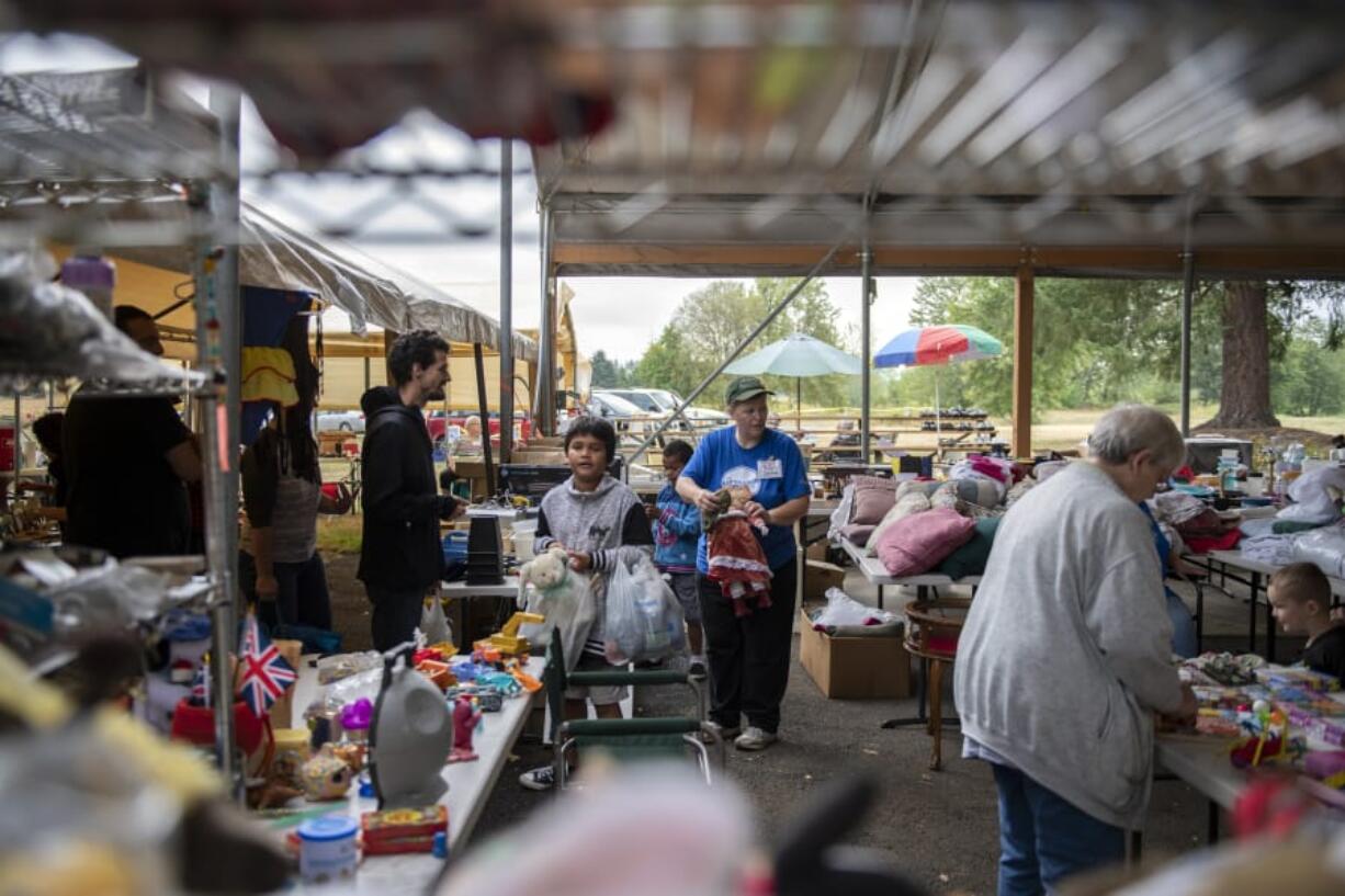 Shoppers and volunteers mingle under a pavilion during Fourth Plain Church of the Nazarene’s sixth annual Care 2 Share event where items are given away free to the community.