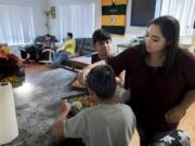 Giovanni Valtierra, 14, left, waits for Vanessa Contreras to finish pouring teriyaki sauce before eating dinner with the rest of his family at their Vancouver apartment on Tuesday evening.