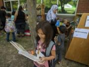 Vancouver resident Shahed Alhariri, 8, dives into a good story Wednesday afternoon while visiting the free book nook with her family during the annual “Go Ready!” back-to-school event at Hudson’s Bay High School. The annual event, now in its fifth year, attracts thousands of families with free resources including haircuts, clothes and immunizations.