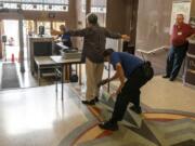 Courthouse security officer Brian Aranda, middle right, uses a hand-held metal detector on a visitor, while information desk volunteer Bob Weller, right, waits at his desk at the Clark County Courthouse on Thursday morning.