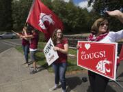 Jessica Wells, program coordinator for development and alumni relations, center, joins Lisa Abrahamsson, assistant director of development and alumni relations, right, as they welcome incoming students on their first day back to campus at Washington State University Vancouver on Monday afternoon.