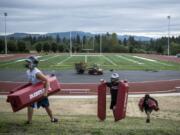 Union players carry drill obstacles from the Union High football field during the first fall practice of the year on Wednesday, Aug. 22, 2019.