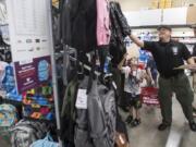 Mitchell Middleton, 6, waits for Clark County sheriff’s Deputy Brad Robinson to grab a backpack from the top rack during Tuesday morning’s Shop with a Cop event at Office Depot in Hazel Dell.