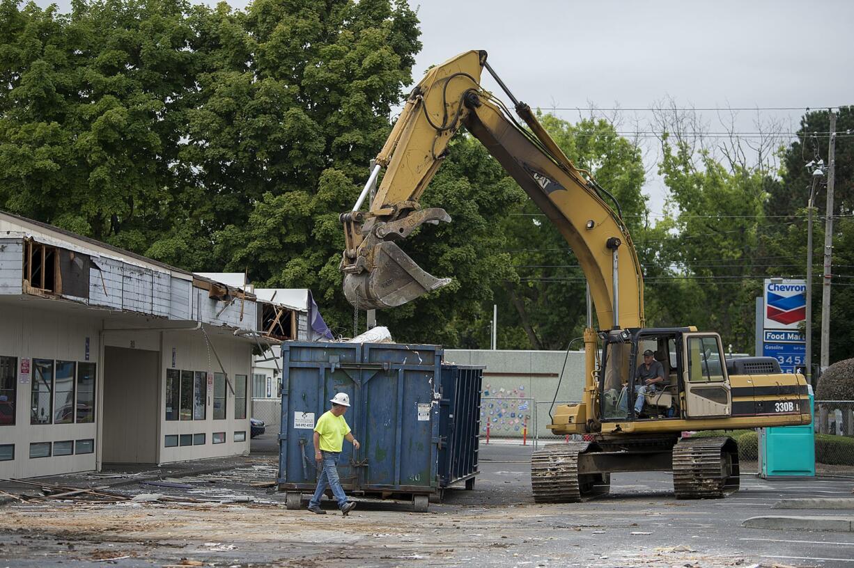 Construction workers help demolish the cluster of strip mall buildings that housed the former FedEx Office Print & Ship Center and other businesses in downtown Vancouver on Wednesday morning, Aug. 21, 2019. The FedEx store was relocated next door in the current Al Angelo building. Al Angelo is leading development on a second office tower at the site.